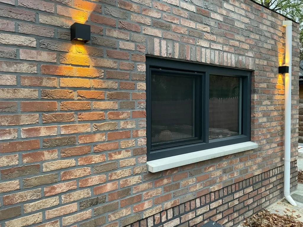 Antracietkleurig kozijn met twee raamvlakken in een bakstenen gevel